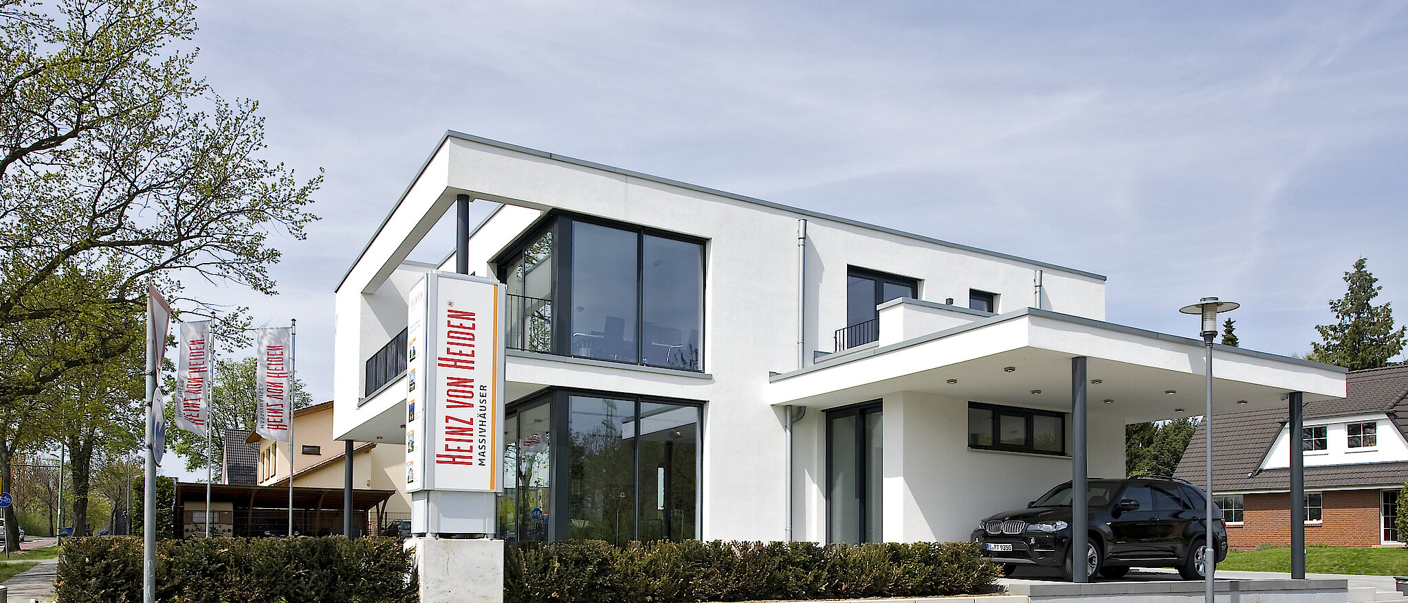 Außenansicht des Musterhauses Ahrensfelde mit Garten und Terrasse.