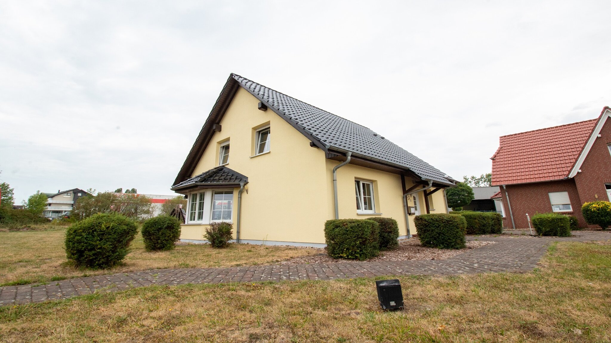 Zweigeschossiges Haus mit Erker, Satteldach und gelber Fassade.