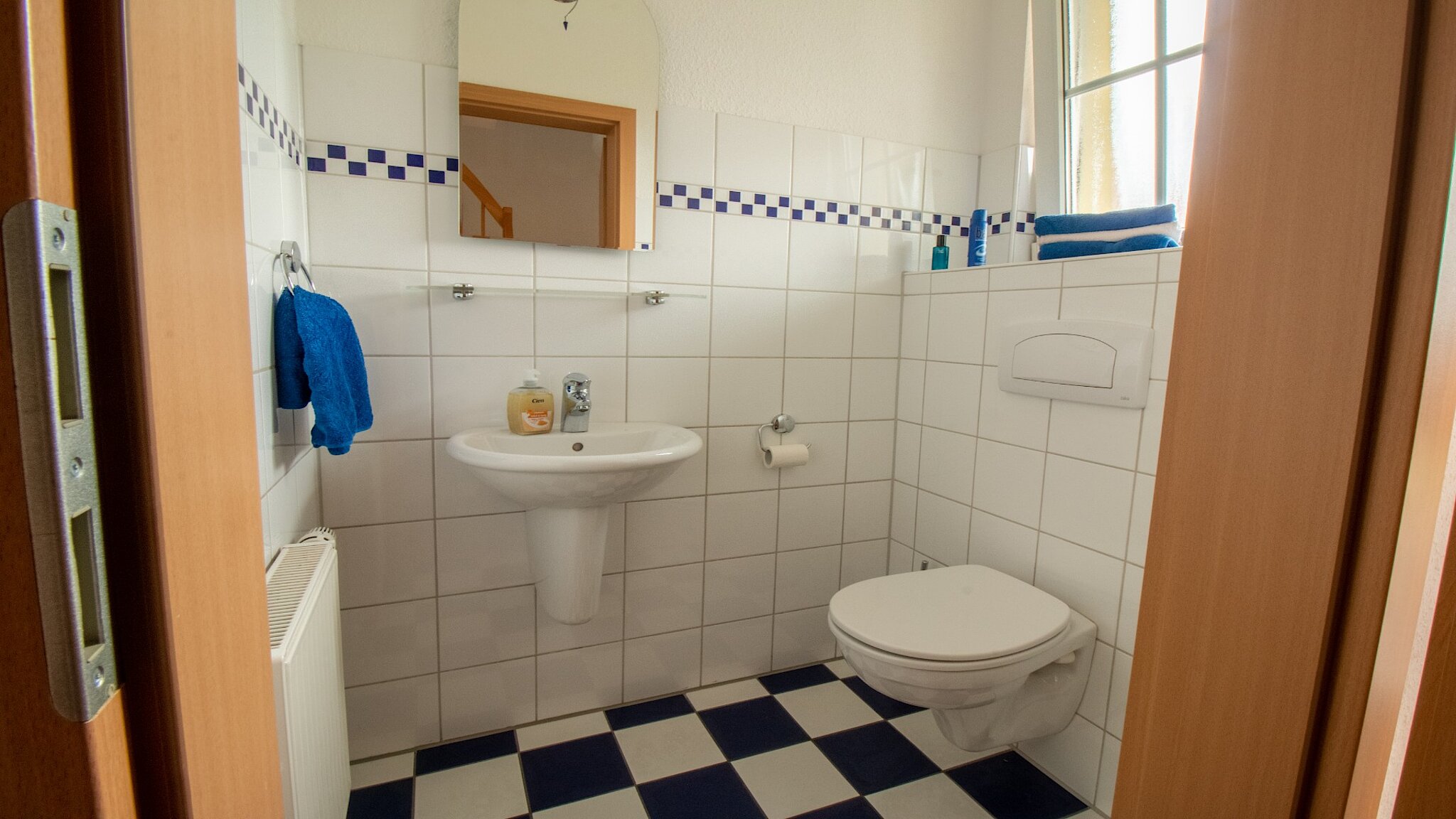 Gefliestes Gäste-WC mit kleinem Waschbecken und Toilette.