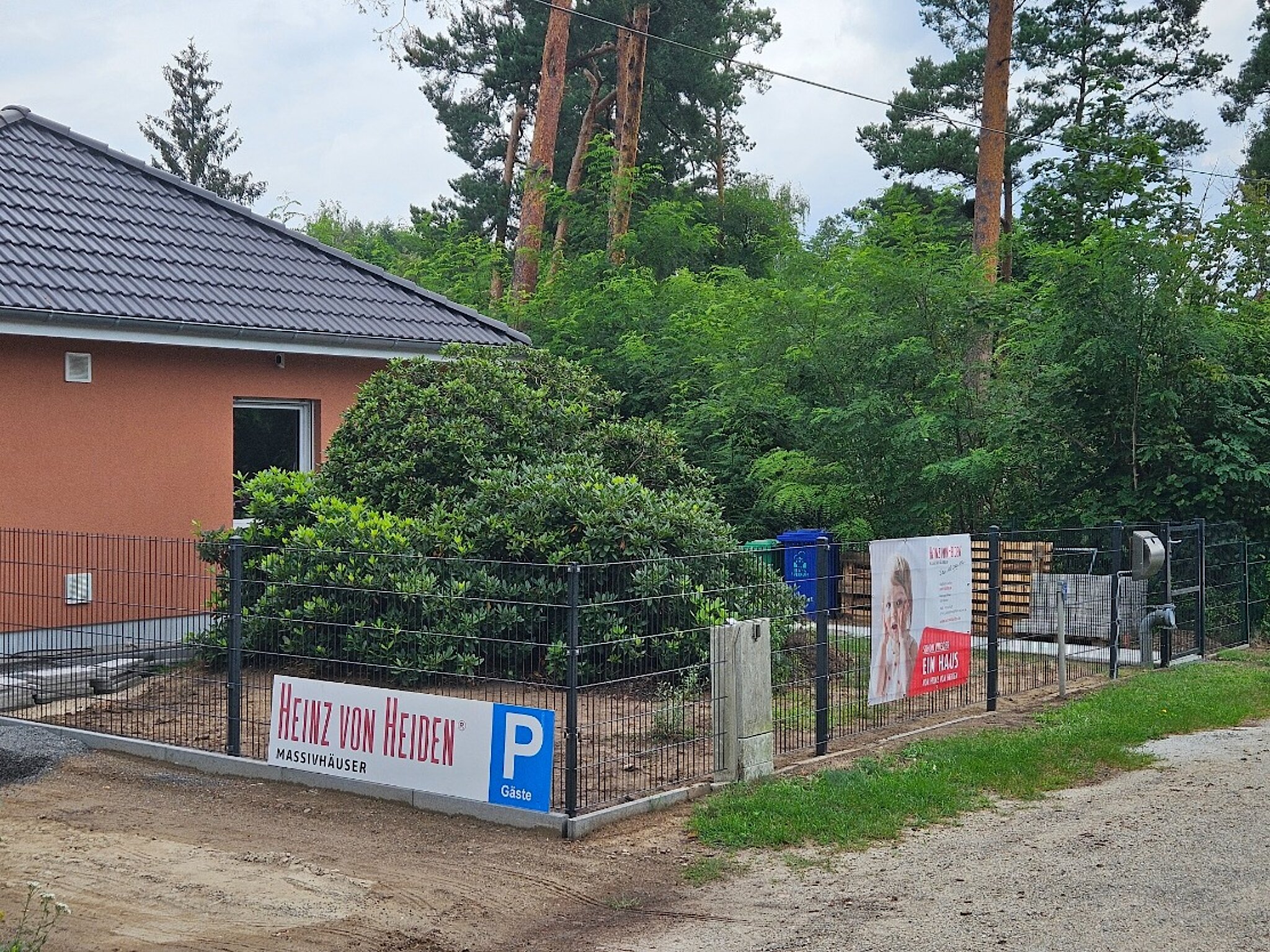 Außenansicht des Stadtbüros Köris mit schwarzem Zaun und Garten. 