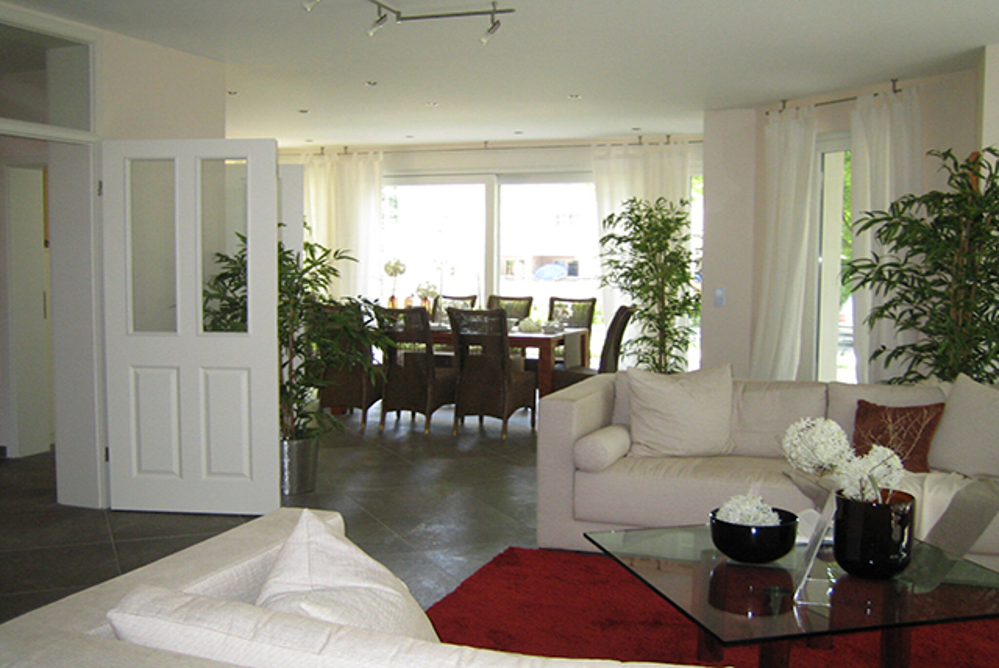 Wohnbereich mit rotem Teppich und weißen Sofas im Musterhaus Strausberg. 