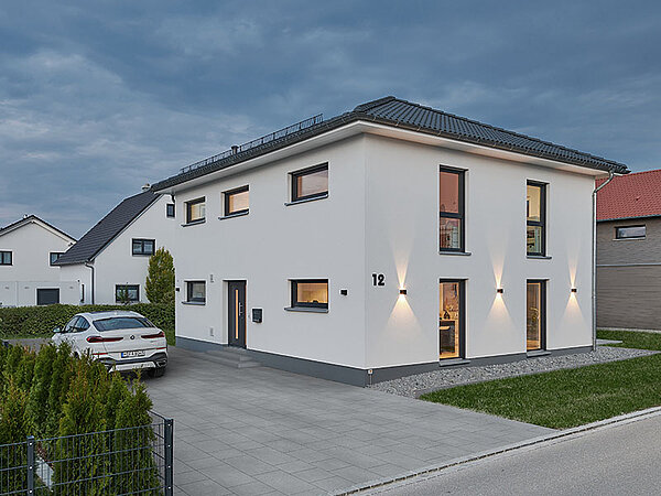 Ansicht eines Hauses, links daneben ein Auto in der Einfahrt